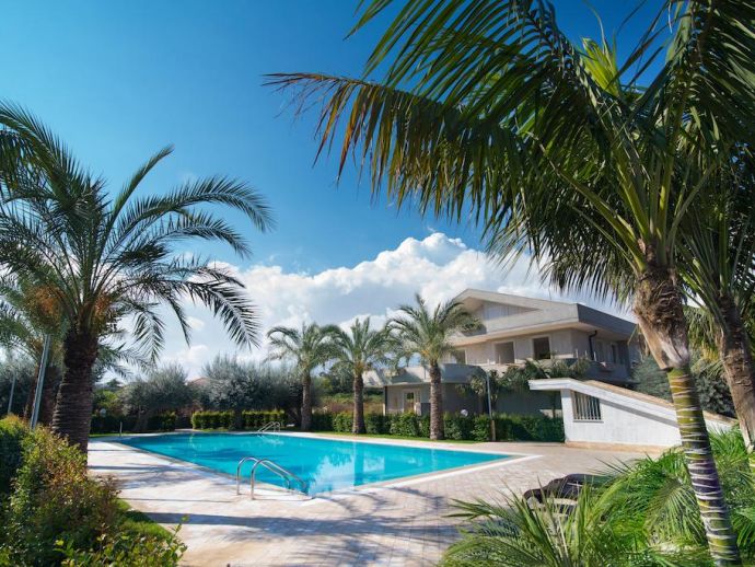 Large communal pool surrounded by mediterranean vegetation